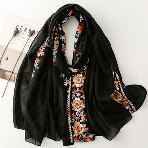 Close-up of exquisite floral embroidery on a black cotton linen shawl with ethnic patterns