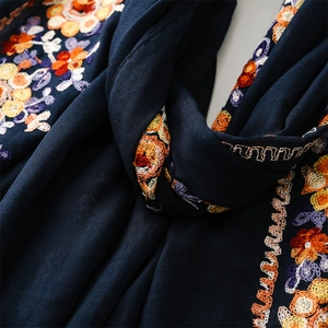 Close-up of navy blue scarf featuring intricate floral embroidery and wavy hem detail