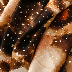 Detail of pashmina scarf fabric showing gold foil stamping and brown leopard texture