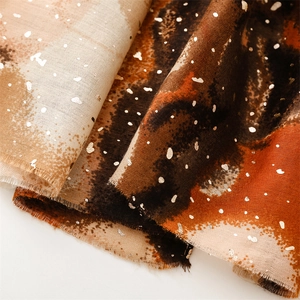 Close-up of artistic cotton-linen scarf with golden foil dots and frayed edges