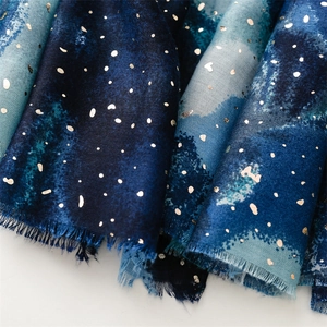 Detail of dark blue watercolor scarf with gold foil dots and frayed edges texture