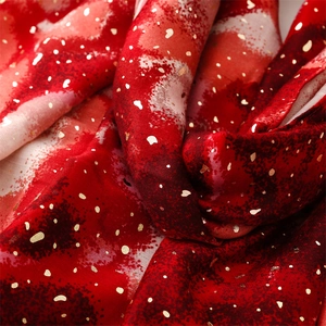 Macro view of soft red gradient scarf fabric featuring shimmering gold foil star accents