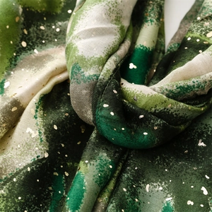 Detail of green cotton linen scarf featuring gold foil dots and artistic abstract texture