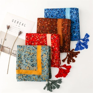 Detail view of cotton-linen scarves in four colors with floral prints and tassel fringe