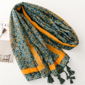 Detail of dark green scarf with floral pattern, orange borders and corner tassels