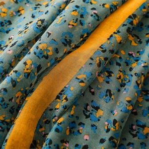 Detailed macro view of floral cotton linen scarf with orange border and green base