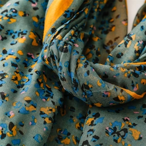 Close-up of floral print cotton scarf with orange border showing soft fabric texture