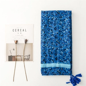 Detail of blue floral cotton scarf featuring light blue borders and dark blue tassels