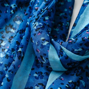 Macro detail of soft cotton-linen scarf with blue leopard print and fine fabric texture