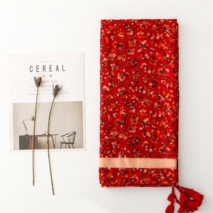 Detail of red floral scarf with fringe tassels and soft linen-feel fabric texture