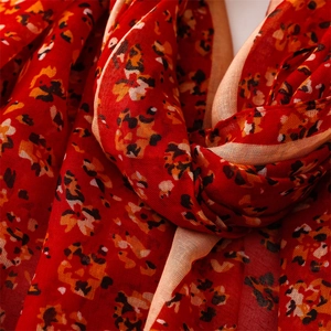 Close-up of lightweight red scarf with floral print showing fabric texture and rolled edges