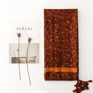 Detail of dark red floral scarf with tassel edges and rustic cotton-linen texture