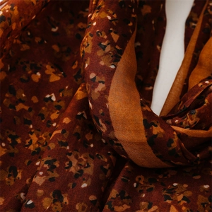 Close-up of abstract floral scarf showing soft cotton-linen texture and caramel brown print