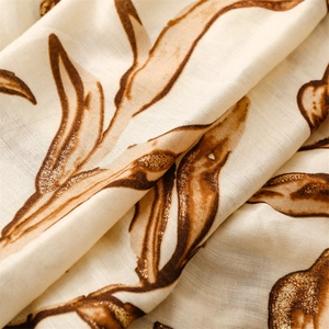 Close-up of beige cotton linen scarf with brown leaf prints and golden glitter finish