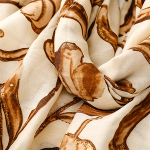 Detailed close-up of beige linen-feel scarf with gold foil floral patterns and fine texture