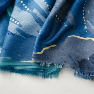 Vista macro di sciarpa blu con pois dorati e bordi con frange naturali