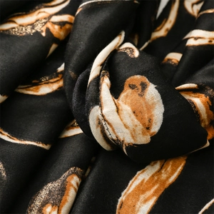 Macro detail of black scarf fabric with golden glitter feather patterns and texture