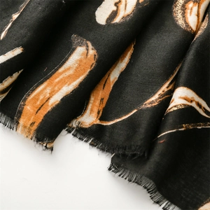 Detail of black cotton linen scarf with gold feather pattern and fringe edges