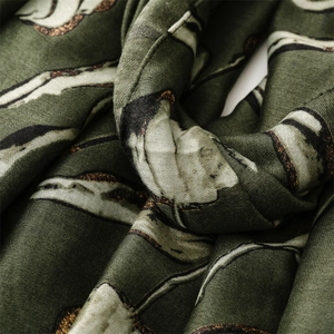 Macro detail of dark green scarf showing linen texture and golden floral foil print