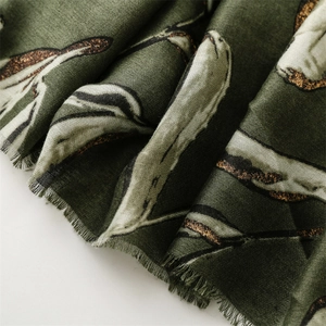 Detail of dark green scarf showing creamy white leaf pattern with gold glitter outlines