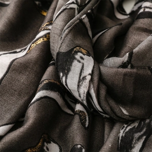 Close-up of soft scarf texture with metallic gold foil penguin pattern on dark grey fabric