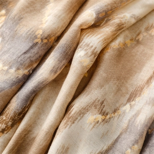 Close-up of linen-feel scarf with golden foil mountain waves and earth-tone gradients