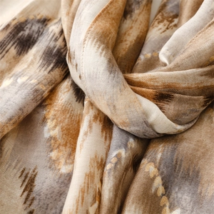 Detailed view of scarf featuring gold foil accents on brown and beige ripple patterns
