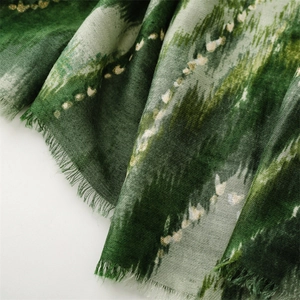 Detail of dark green wave pattern scarf with metallic accents and soft fringe edges