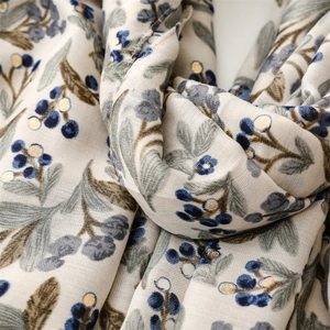 Detailed view of soft linen scarf featuring vintage berry floral patterns and golden accents