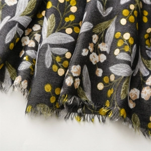 Detail of dark grey scarf showing white leaf prints, gold berries and frayed edges