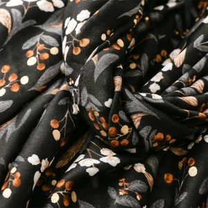 Macro shot of cotton linen scarf texture featuring orange berries and white floral patterns