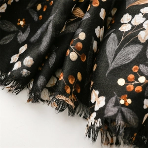 Close-up of black cotton-linen scarf with floral berry print and frayed tassel edges