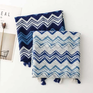 Detail of blue geometric wave pattern scarf with delicate tassel fringe on white background
