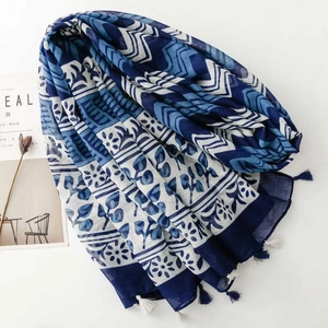 Detailed view of blue and white geometric floral scarf with decorative tassels