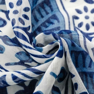 Detailed view of blue and white floral porcelain pattern on soft tassel scarf fabric
