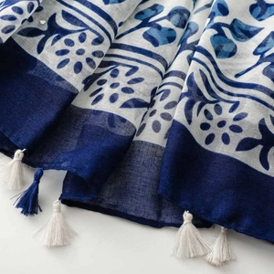 Detail of blue and white porcelain pattern fabric with delicate white cotton tassels