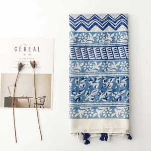 Detail of blue and white floral scarf with geometric patterns and tassel fringe