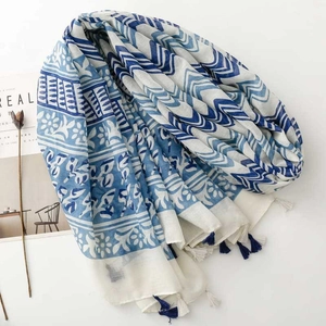 Close-up of blue and white geometric scarf with delicate navy tassels and floral prints