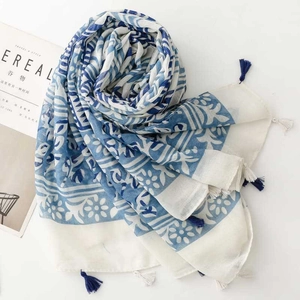 Detail of blue and white floral scarf with fringe edge next to a lifestyle magazine