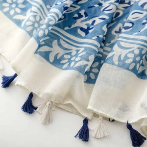 Detailed close-up of blue floral patterns and white fringe tassels on a cotton scarf