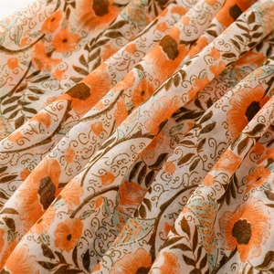 Close-up of lightweight floral scarf with orange daisy print and delicate tassel edges
