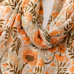 Detail of floral printed scarf showing soft orange flower texture and breathable fabric