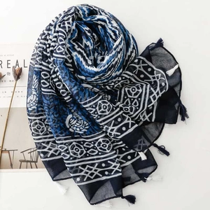 Detail of dark blue geometric wavy patterns and tassels on a lightweight ethnic scarf