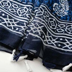 Detail of blue and white paisley pattern scarf with soft fringe tassels and woven texture