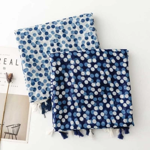 Close-up of blue and white polka dot scarf with tassel fringe on a white background