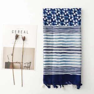 Detailed flat lay of blue polka dot scarf with fringes next to a minimalist magazine
