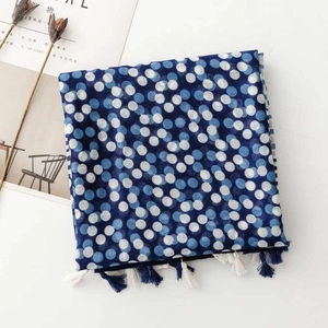 Flat lay of blue polka dot scarf with tassels, styled with a magazine and dried flowers