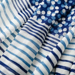 Detail of blue and white scarf featuring geometric stripes, polka dots and tassel texture