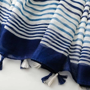 Macro shot of blue and white striped scarf fabric featuring delicate fringe tassel details