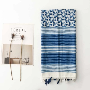 Close-up of blue and white porcelain pattern scarf with polka dots, stripes and tassels
